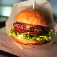 Burger,With,Cheese,On,Wax,Paper,On,Plastic,Tray,On